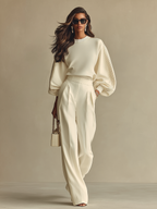 Completo composto da maglione a maniche larghe color crema in maglia morbida e pantaloni a vita alta con pieghe.