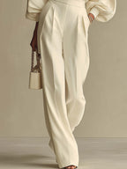 Completo composto da maglione a maniche larghe color crema in maglia morbida e pantaloni a vita alta con pieghe.