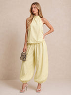 Completo composto da top all'americana e pantaloni a gamba larga in misto lino color giallo chiaro.