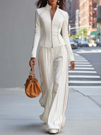 Traje de pantalón blanco con cuello alto y cremallera, pernera ancha.
