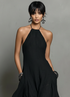 Vestido largo negro de lino con escote halter, falda fluida y bolsillos laterales.